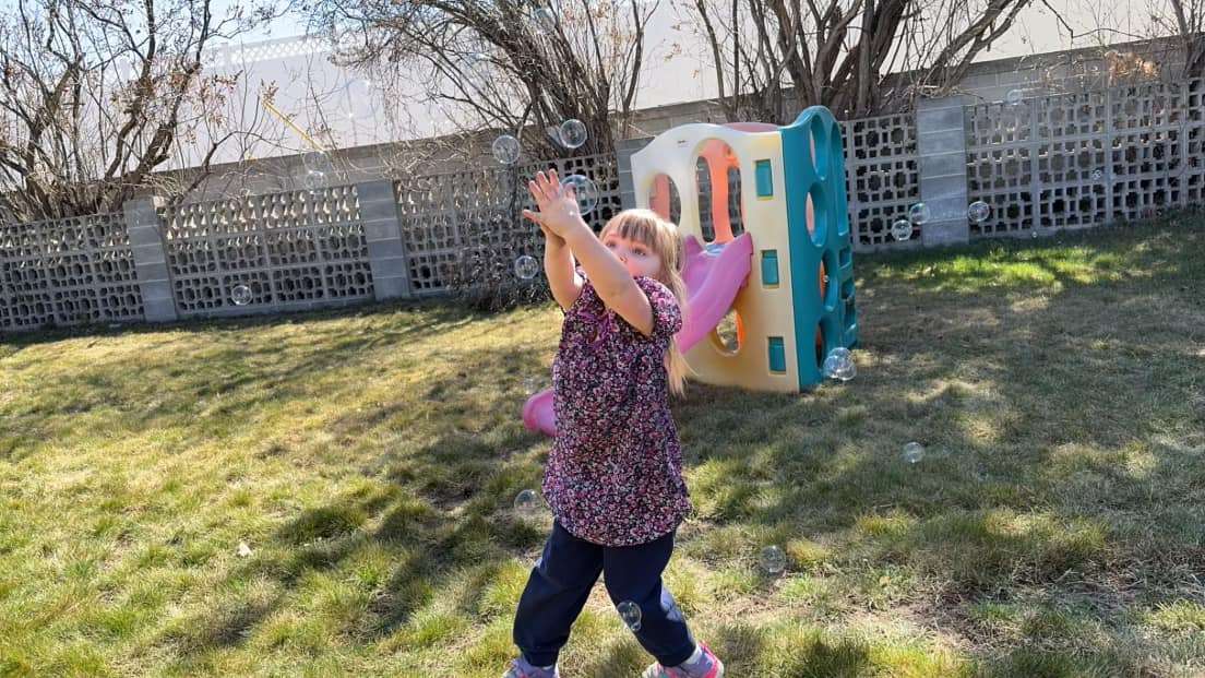 Child catching bubbles during play at a toddler care center in Filer, ID