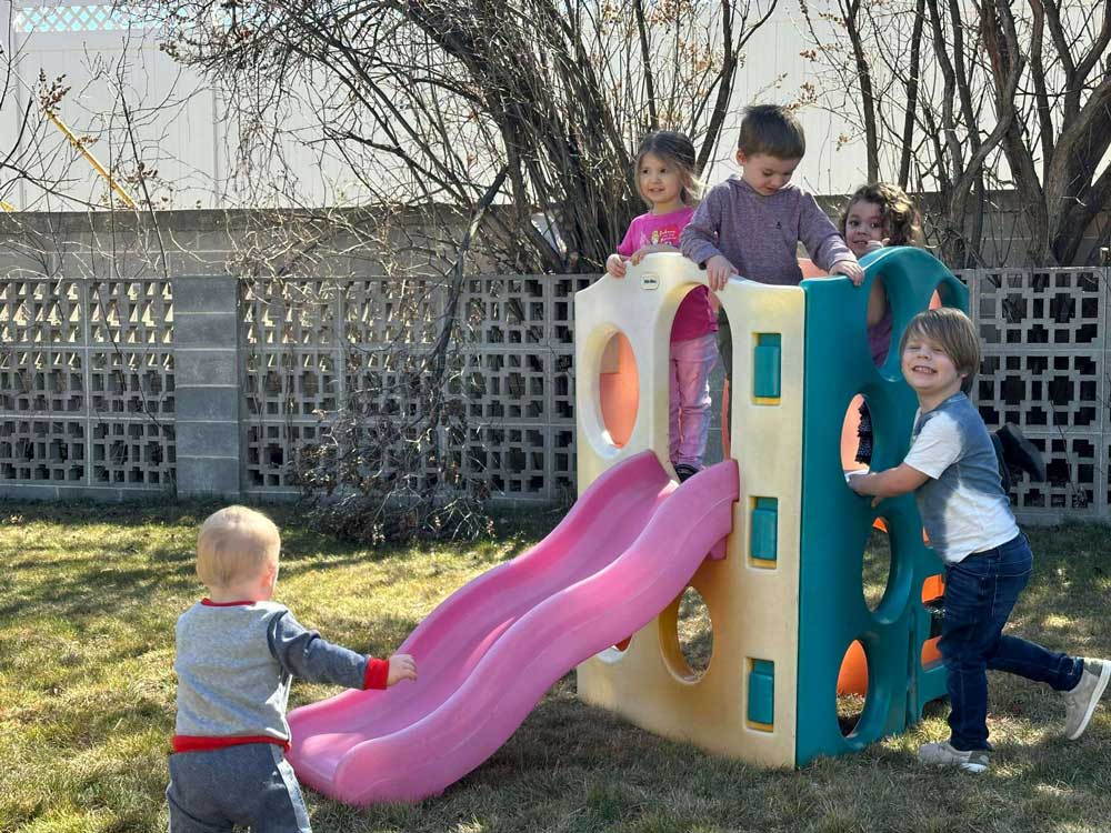 Children sliding on a playground at a licensed toddler care center in Twin Falls, ID